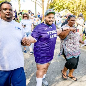 A son stands between his parents as they walk down the road at a busy event