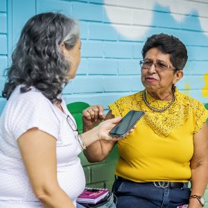 Two women having a conversation while one holds a phone up in front of her