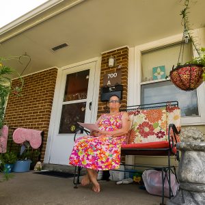 Woman sits on front porch of a rural apartment