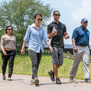 Four people talk with each other while walking down an outdoor path