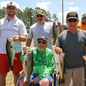 A group of four men, one in a wheelchair, each hold a fish