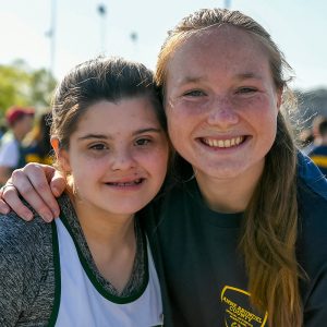 Two young girls, one with a visible disability and one without, smile for the camera