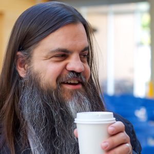 Man smiles and holds coffee