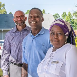 A woman and two men wearing business casual clothing smile for the camera