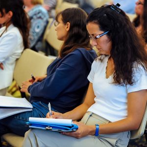 Woman writes on paper pad at a meeting