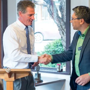 Two men at Rotary Club meeting shake hands at the podium