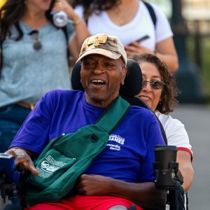 Man in wheelchair smiles while woman pushes him