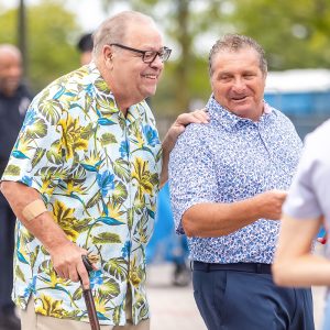 Man using a cane walks alongside another man while laughing