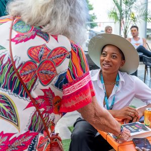 Woman leans over talking to a woman sitting at a table