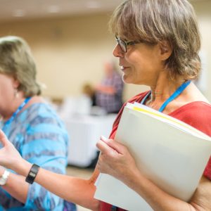 Woman holding a folder full of papers talking to someone out of frame