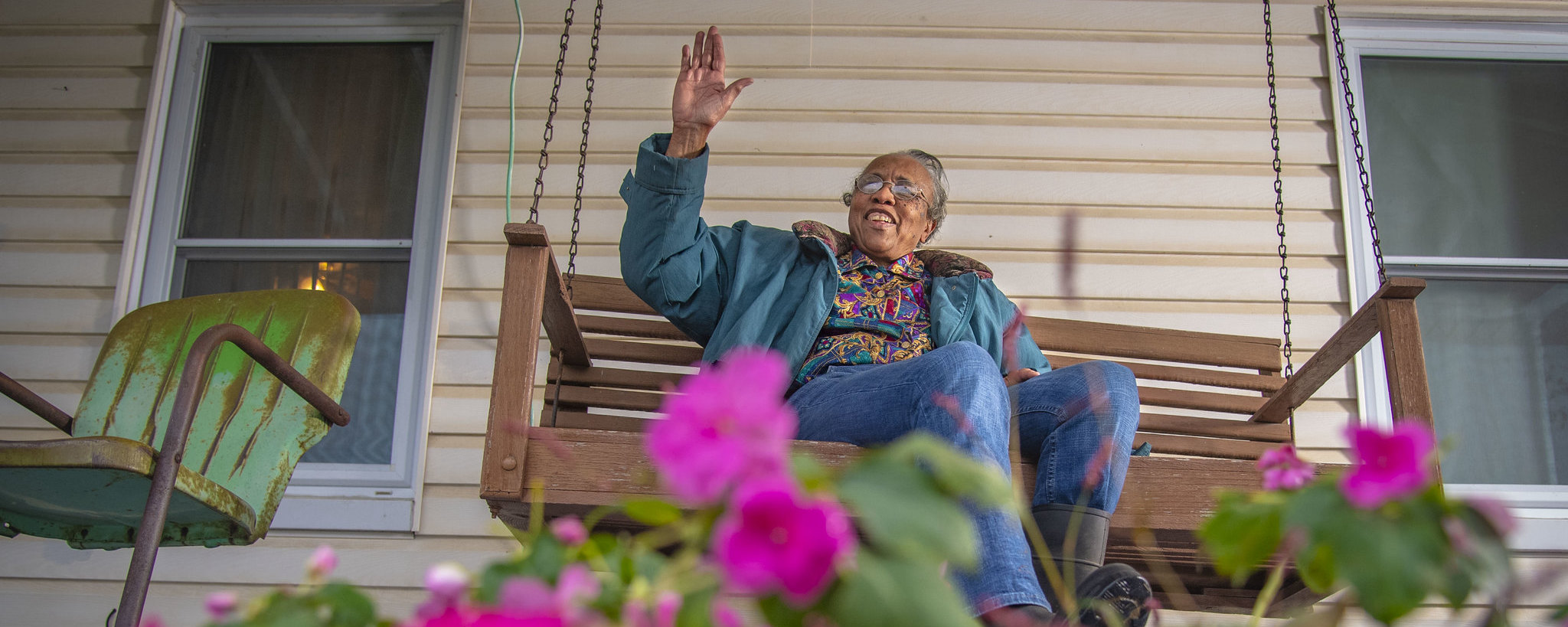 Woman sitting on a porch swing waving